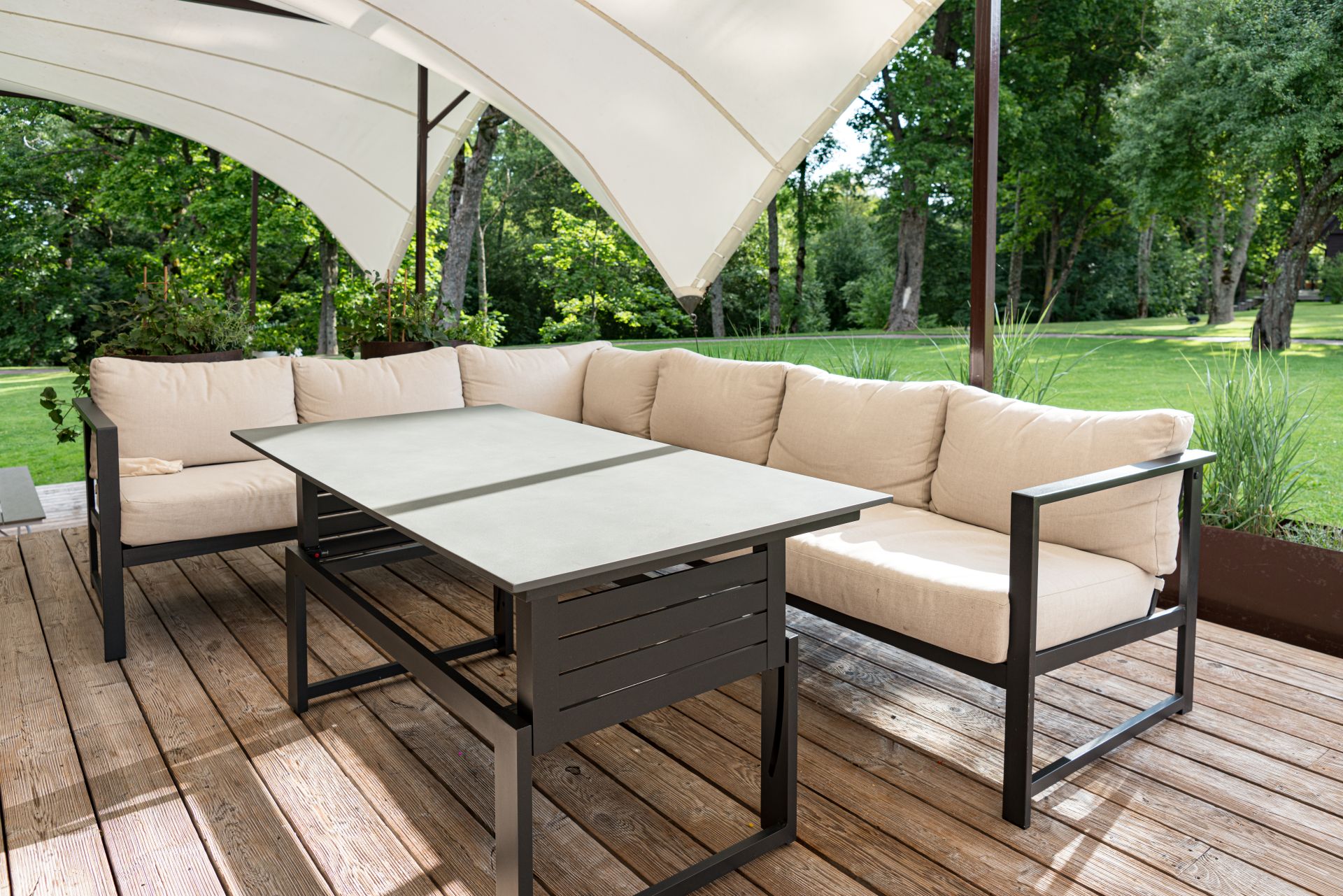 Moderne Terrassenlounge mit beigem Sofa und elegantem Beschattungssystem, ideal fuer stilbewusste Gestaltung mit Sonnensegel nach Mass.